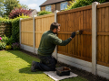 Professional contractor applying protective wood stain to garden fencing as part of Fencing Services in Eastbourne.