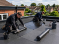 Professional roofers installing a flat roofing system on a residential or commercial property in Eastbourne.