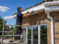 Professional installer fitting new PVCu soffits, fascias, and guttering on a residential property in Eastbourne.