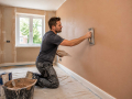 Professional plasterer completing Plastering and Screeding in Eastbourne with a smooth wall finish ready for decoration.