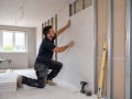 Professional Plasterers and Dry Lining Contractors in Eastbourne installing plasterboard and preparing an interior wall for finishing.