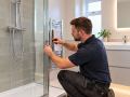 Bathroom Installations in Eastbourne with an installer fitting a glass shower enclosure