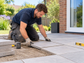 Driveways and Patios in Eastbourne with a landscaper laying paving slabs beside a home