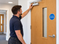 Fire Doors in Eastbourne with a tradesperson checking the overhead door closer